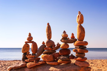 Several Rock zen pyramids of colorful pebbles standing on the beach, on the background of the sea. Concept of balance, harmony and meditation.