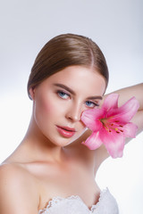 Fototapeta na wymiar Beauty girl with pink lily flower near the face. . Cosmetics and cosmetology.