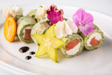Pancakes rolls stuffed with salmon, spinach, Philadelphia cheese. Banquet festive dishes. Gourmet restaurant menu. White background.