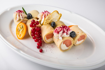 Pancakes rolls stuffed with salmon, spinach, Philadelphia cheese. Banquet festive dishes. Gourmet restaurant menu. White background.