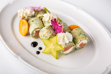 Pancakes rolls stuffed with salmon, spinach, Philadelphia cheese. Banquet festive dishes. Gourmet restaurant menu. White background.