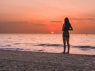 Fototapeta premium young girl on the beach watching the sunset