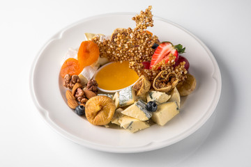 Luxurious cheese plate of different types of cheese: camembert, dorblu, parmesan, cheddar, with honey, caramel, berries. Banquet festive dishes. Gourmet restaurant menu. White background.