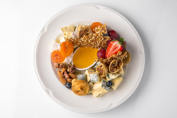 Luxurious cheese plate of different types of cheese: camembert, dorblu, parmesan, cheddar, with honey, caramel, berries. Banquet festive dishes. Gourmet restaurant menu. White background.