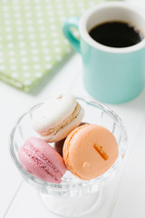 白い木目の板のに置かれたマカロンとコーヒー