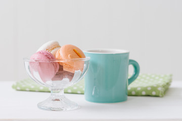 白い木目の板のに置かれたマカロンとコーヒー