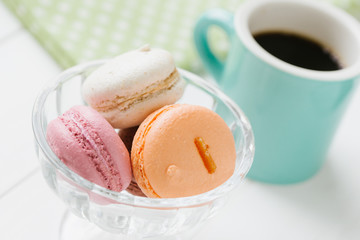 白い木目の板のに置かれたマカロンとコーヒー