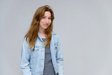 Portrait to waist of a young pretty brunette girl woman with beautiful long hair on a white background in a jacket from jeans. He talks, smiles, shows his hands with emotions in various poses.