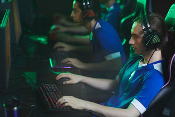 Young focused cyber gamer in headset sitting in gaming chair and using keyboard and mouse while playing video game during tournament © Seventyfour