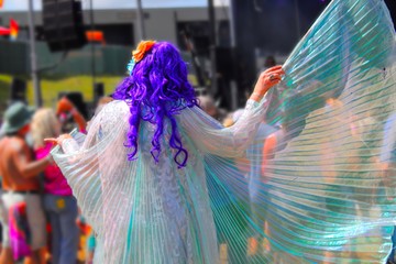 Beautiful Woman dressed in Gossamer wings and sequin dress dancing at a music festival, bokeh focus 