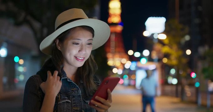 Woman use of mobile phone in Tokyo city at night