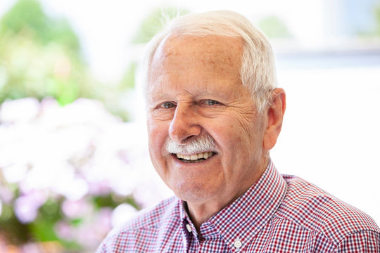 portrait of senior, old men smile and is relaxed in his garden with a white wand
