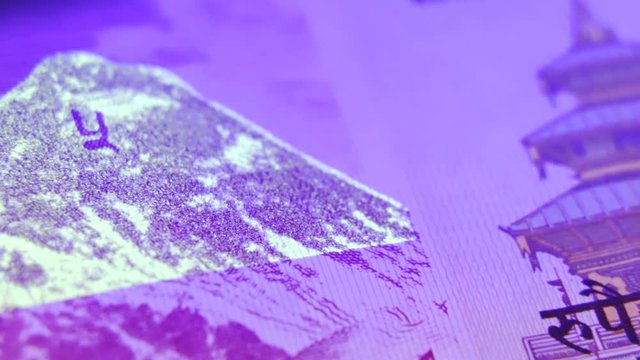Shiny nepalese rupee of 5 denomination under Ultra Violet blacklight, close up pan