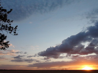 The natural picture of the combination of rainbow colors in the cloudy evening sky under the rays of the sun that sits behind the horizon.