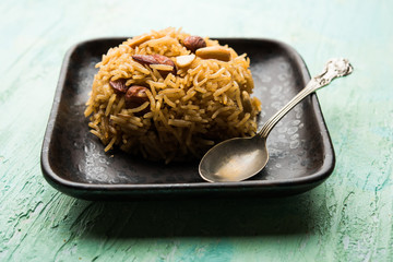 Traditional Jaggery Rice or Gur wale chawal in Hindi, served in a bowl with spoon. selective focus
