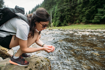 girl travels drinking water from a mountain river