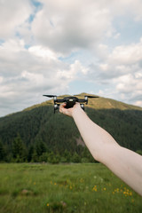 the hand holds a drone against the background of the mountains