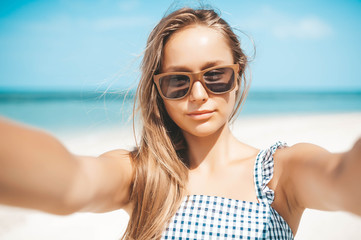 Beautiful young woman doing selfie on the beach