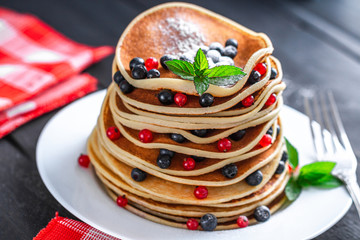 Homemade pancakes with berries and powdered sugar for breakfast