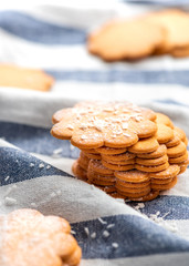 Stack freshly baked flat cookies on a blue striped tablecloth