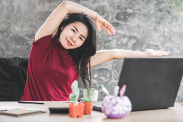 Asian female business woman stretching arm and body relaxing at office desk 