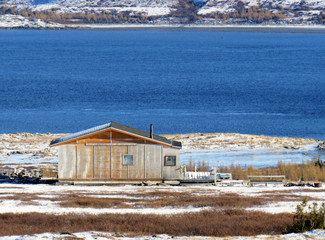 Fototapeta na wymiar Wood cabin by the blue water in Nunavik in the Fall