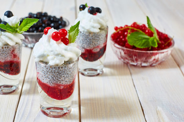 On the table standing a glass of black currant dessert, cream and chia seeds.