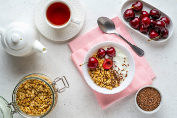 Healthy breakfast with greek yogurt, granola (muesli), flax seeds, cherries and tea. Health care, fitness, diet concept.