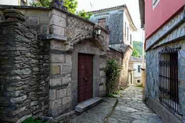 Fototapeta na wymiar Ampelakia, Greece - May 18, 2019: Traditional architecture in a narrow street of Ampelakia, a village famous in the 18th century for its great commercial activities