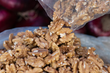 Adding new fresh walnut seeds to a pile for sale. Healthy natural food