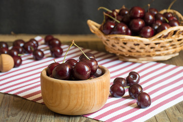 Close up of organic fresh sweet cherries in wooden bowl, farm fruits on farmer market table. Healthy food consept