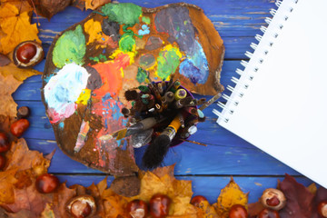 Painter workplace in autumn park with palette, paper pad and paintbrushes.