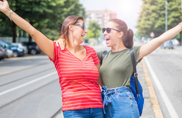 Portrait of two young beautiful  smiling girls in a summer day whit colored t-shirt clothes and jeans