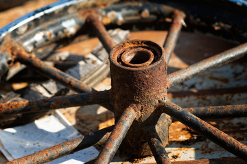 Old, used, rusty metal cart wheel. Wheel hob and spokes. Vintage transport detail