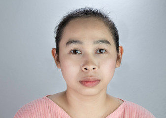 Portrait beautiful face of young woman with being serious in pink shirt on grey background.
