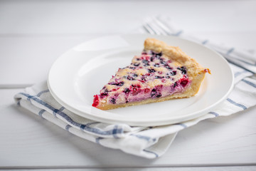 Slice of Blueberry and red currant Pie on rustic wooden table