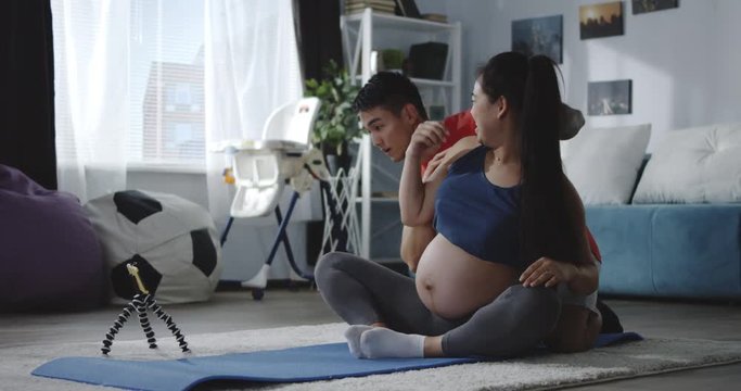 Man and pregnant woman watching video during workout