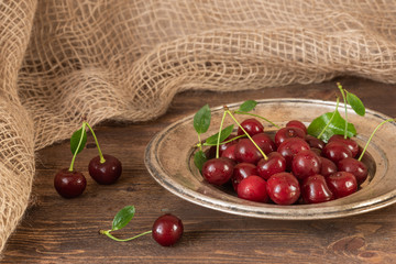 Ripe cherries in an old plate on a wooden background