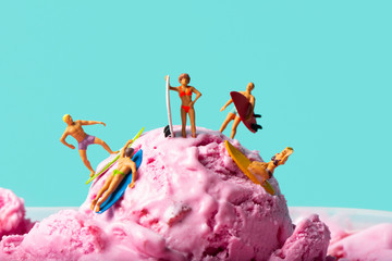 miniature people surfing on an ice cream ball