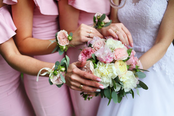 Obraz na płótnie Canvas The bride holds a wedding bouquet in her hands. Hands girlfriends reach for a bouquet. Wedding decorations on hand. Beautiful wedding bouquet in the hands of the bride with delicate peonies. 