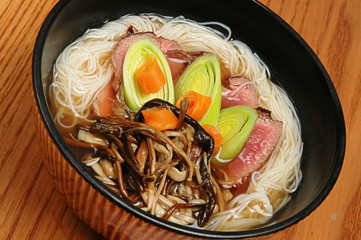 Japanese food udon with noodles and meat in a dark bowl on a wooden background
