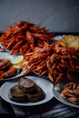two large plates with boiled crayfish, a plate with fried tuna steak, boiled shrimps and fried lobster