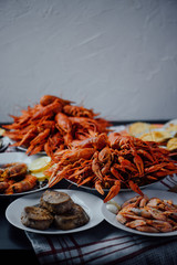 two large plates with boiled crayfish, a plate with fried tuna steak, boiled shrimps and fried lobster
