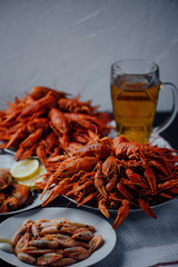 two large plates with boiled crayfish, boiled shrimps, fried lobster and beer