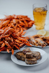 two large plates with boiled crayfish, a plate with fried tuna steak, fried lobster and beer