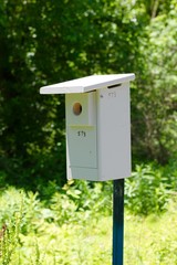 A close view of the old metal box birdhouse on the pole.
