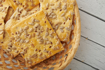 мStack of various crispy wheat, rye and corn flatbread crackers with sesame and sunflower seeds on white wooden background.