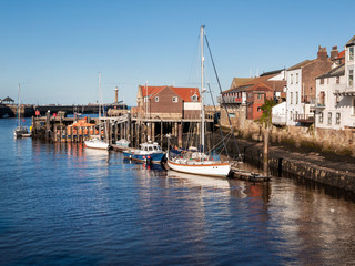 Fototapeta na wymiar The harbour at Whitby with the buildings by the quayside and boats moored up.
