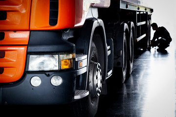 automobile mechanic checking tires and repairing broken semi truck tractor in the garage, selective...