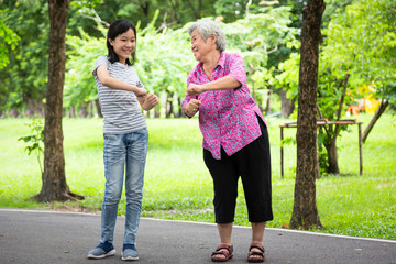 Happy asian little child girl smiling and exercise with elderly woman in outdoor...